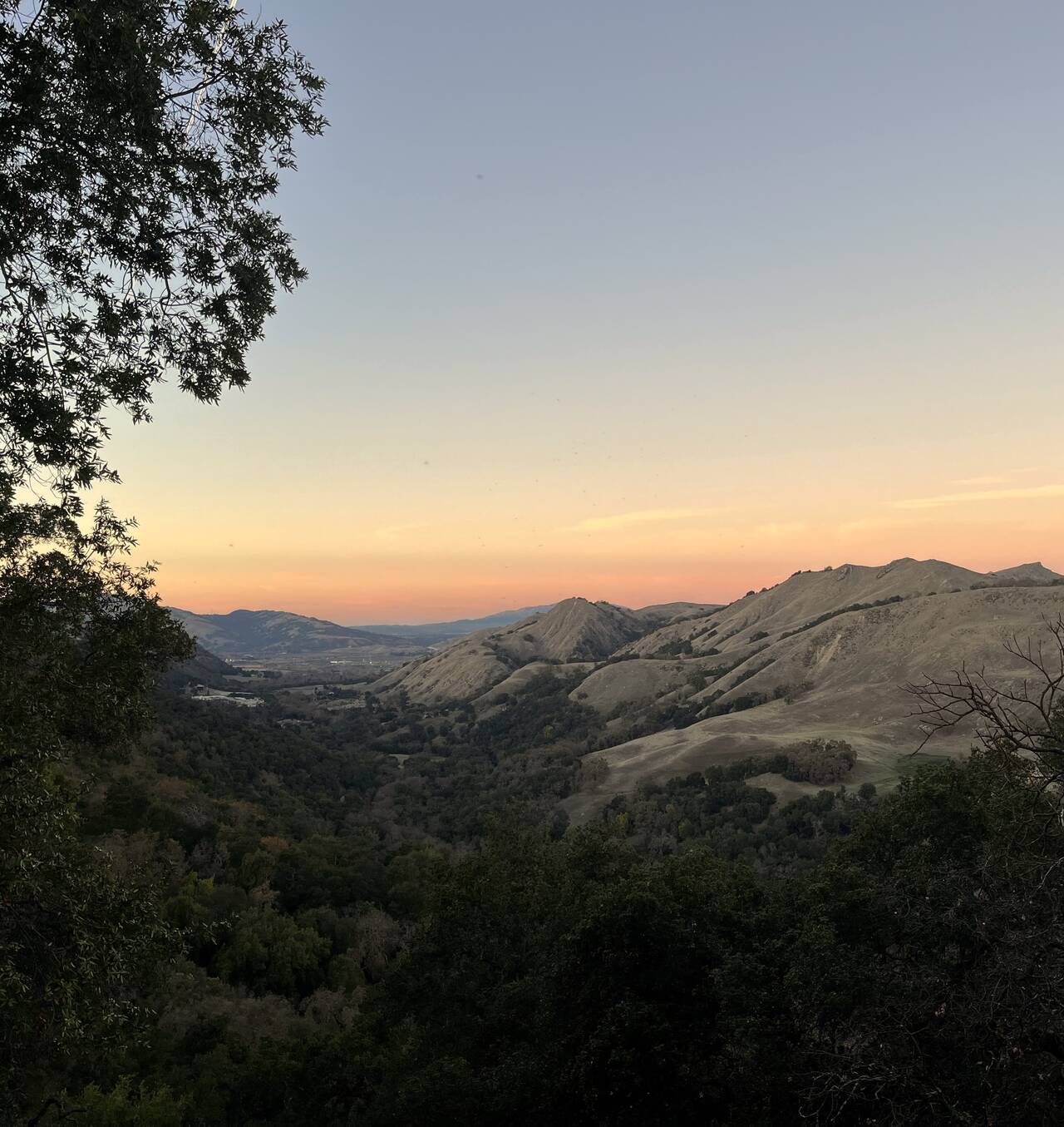 Looking out toward Pleasanton, the setting sun casts a warm glow on the shadowed hills
