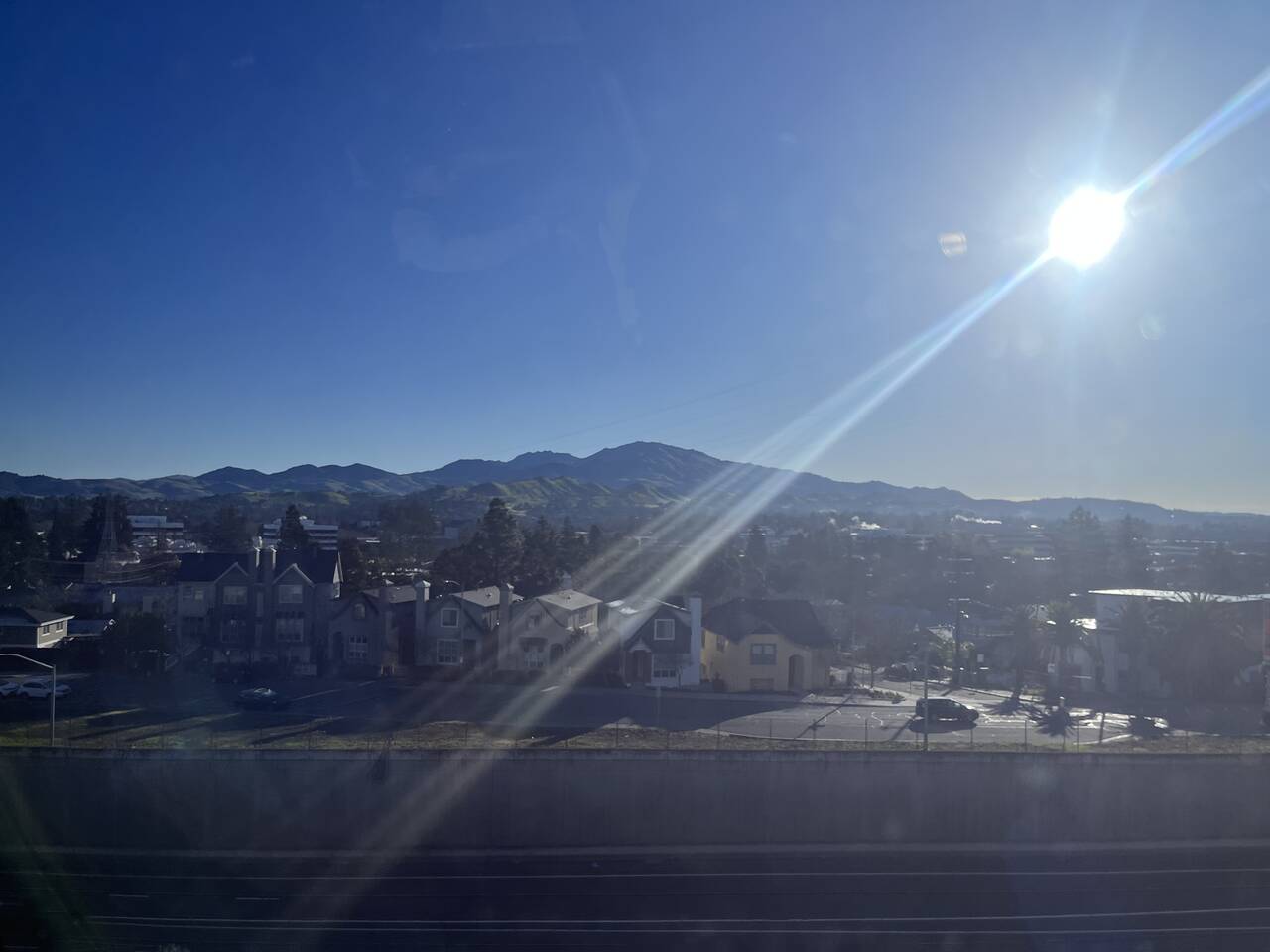 A view out the BART window. A sun flare obscures the photo. Mount Diablo looms on the horizon.