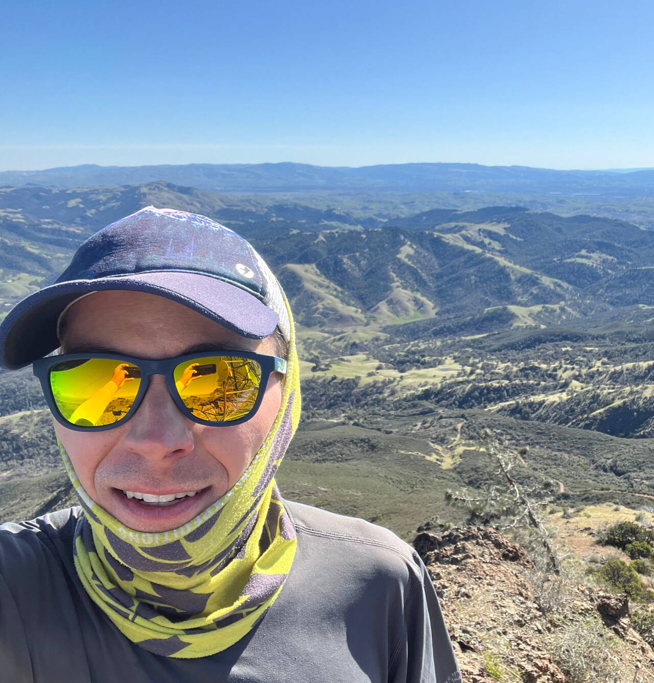 Summit selfie with hills in the background.