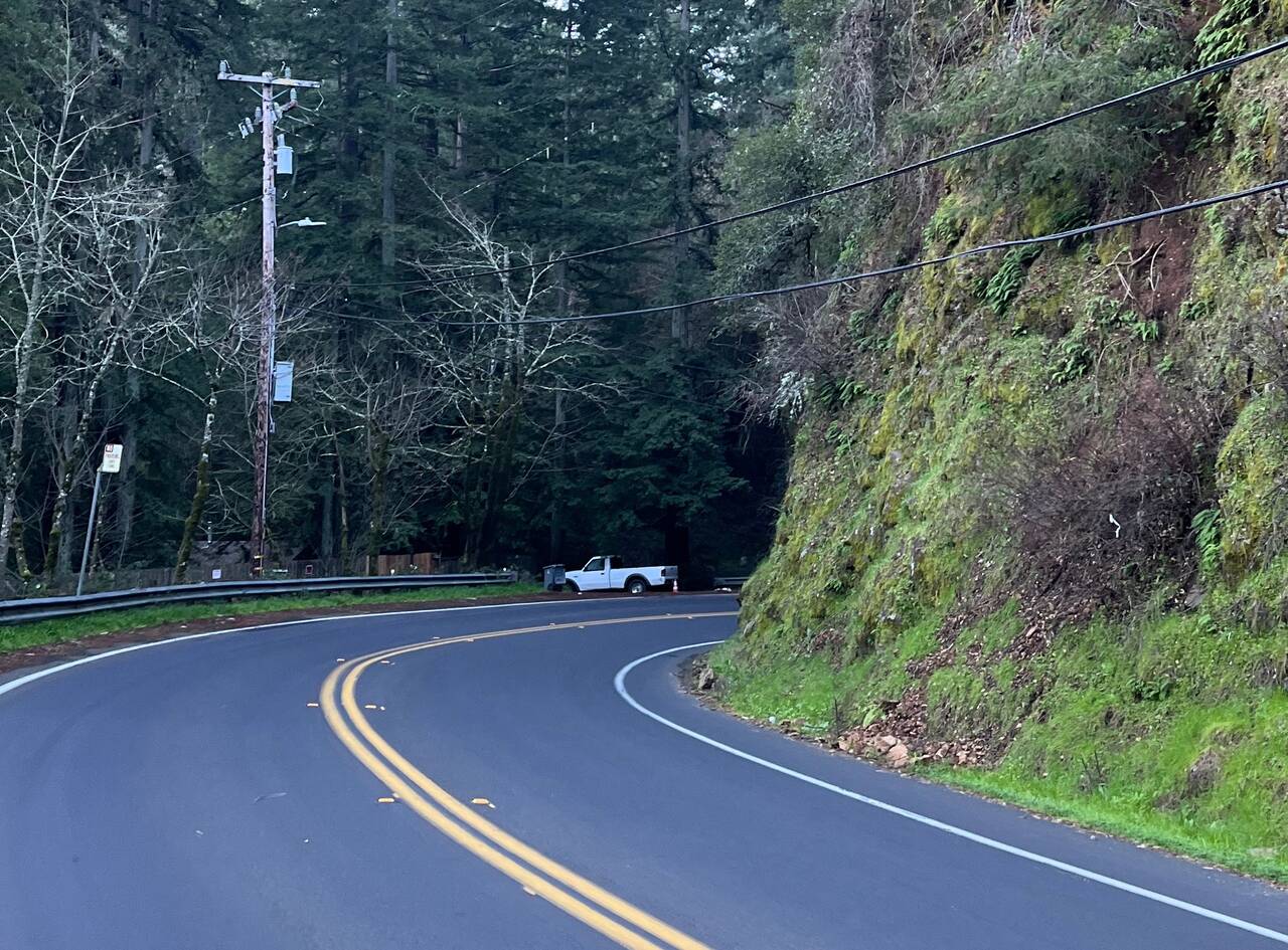 Looking around a bend in the road. A steep hill rises next to the road.